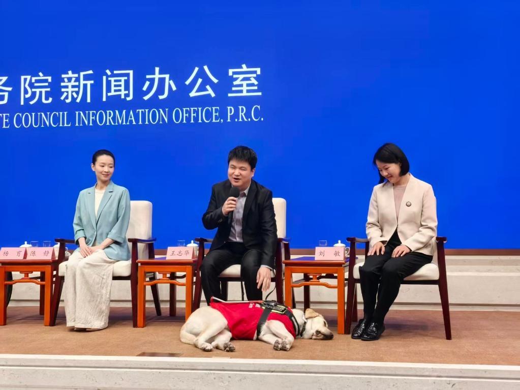 Am 15. Mai 2026 stellte Wang Zhihua im Pressebriefing-Saal des Informationsbueros des Staatsrats die Behindertenhilfe vor; der Blindenfuehrhund Aiju begleitete ihn ruhig an seiner Seite. Bildquelle: Foto des Xinhua-Reporters Wei Guanyu.