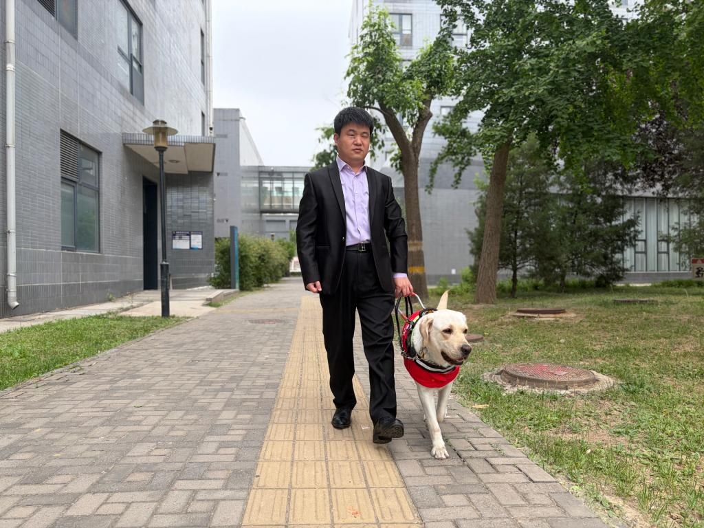 Wang Zhihua bereitet sich darauf vor, unter Fuehrung des Blindenfuehrhundes Aiju zum Treffen mit chinesischen und auslaendischen Journalisten im Informationsbuero des Staatsrats zu gehen. Bildquelle: von Xinhua befragte Person.