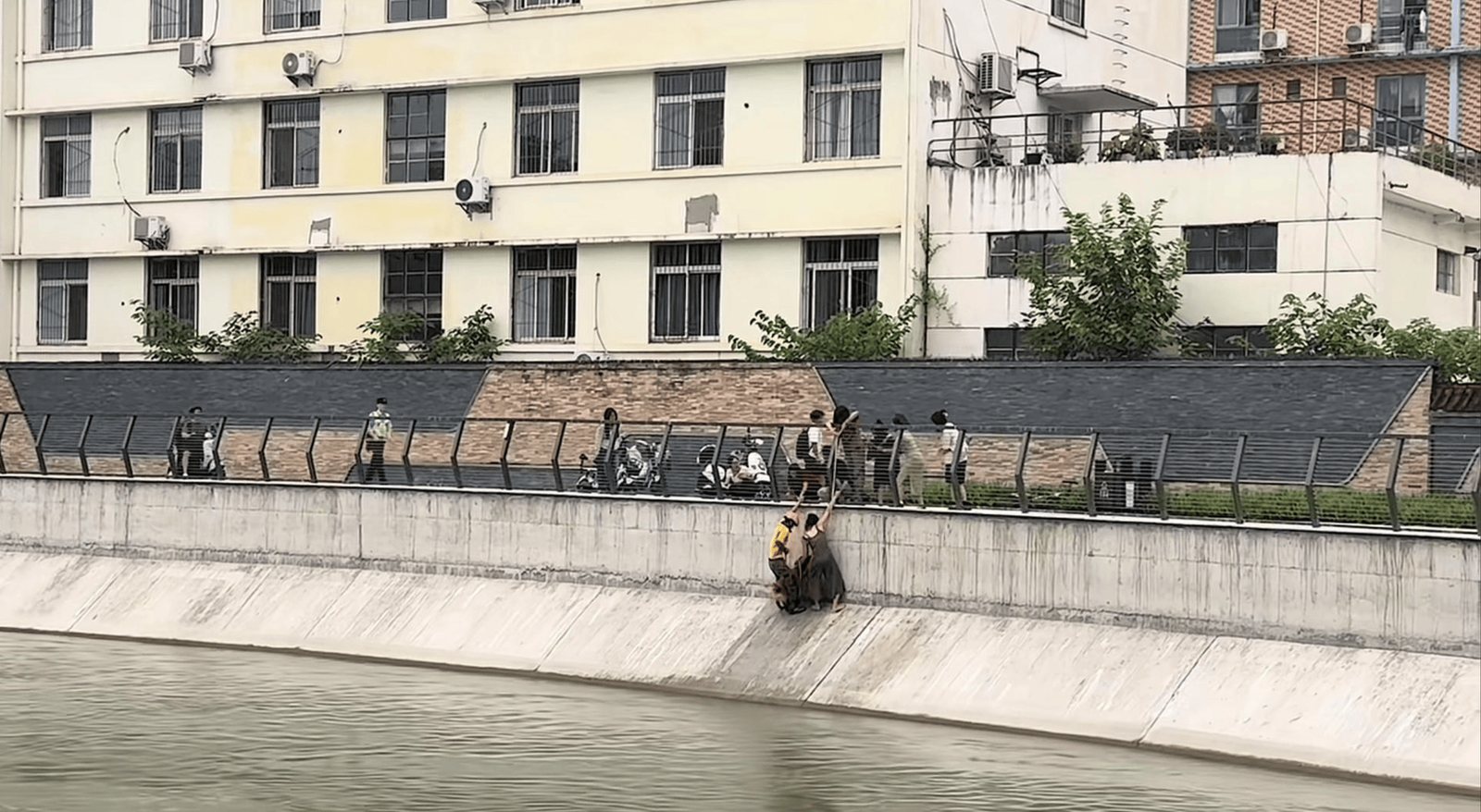 Umgebung am Dongfeng-Kanal in Chengdu; die Rettung geschah zwischen der Boeschung und den Menschen auf der Bruecke. Quelle: Repost-Seite von Red Star News.
