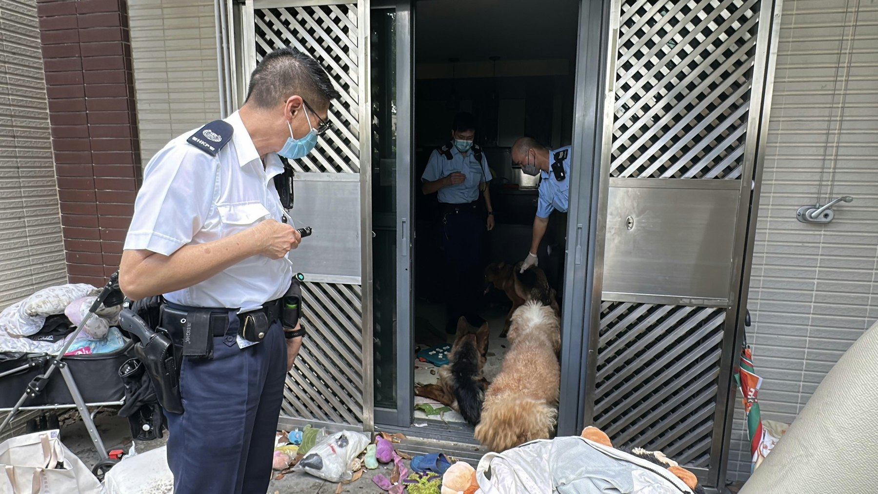 Tin-Shui-Wai-Dorfhausfall mit fuenf Hunden ohne Futter und Wasser, Beamte sehen an der Tuer nach Hunden